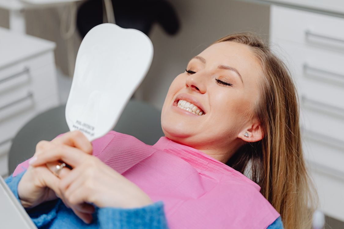 Happy patient checking her smile in a mirror
